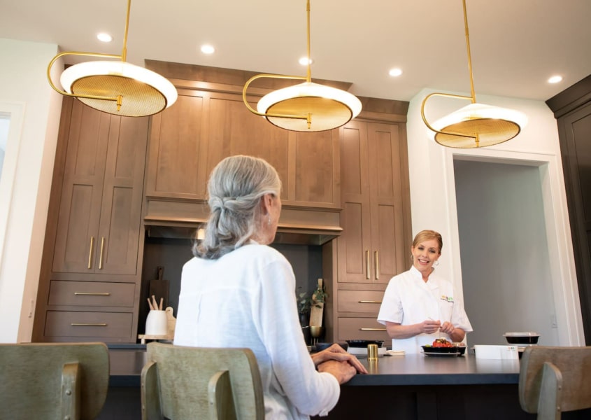 Personal chef talking with her elderly client in a home kitchen.