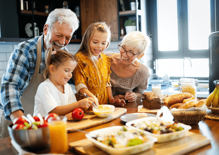 Happy senior couple preparing food with young grandchildren